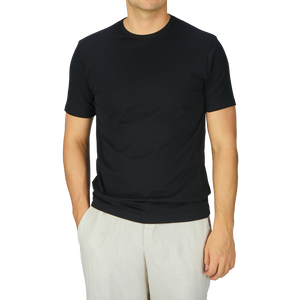 A man wearing a comfortable Sunspel Black Classic Cotton T-Shirt and white pants.