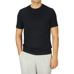 A man wearing a comfortable Sunspel Black Classic Cotton T-Shirt and white pants.