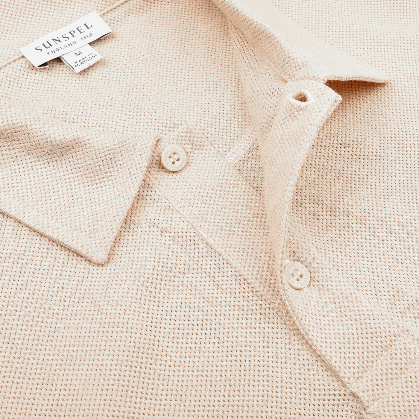 The Ecru Beige Cotton Riviera Polo Shirt by Sunspel is crafted from breathable cotton mesh, featuring button details and the distinctive Sunspel brand label.