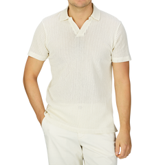 A man wearing a Sunspel Ecru White Linear Cotton Mesh Polo Shirt made of Supima cotton and pants.