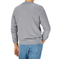 A man in a Sunspel Grey Melange Cotton Loopback Sweatshirt and jeans is seen from behind.