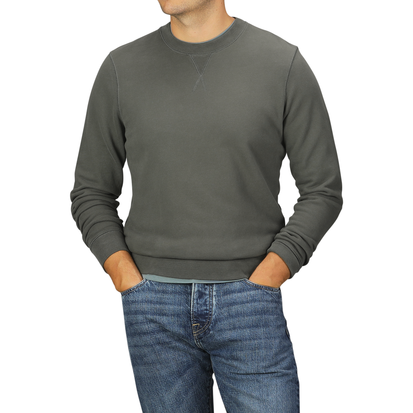 Person wearing a Khaki Green Cotton Loopback Sweatshirt by Sunspel and blue jeans, with hands in pockets, standing against a plain background.