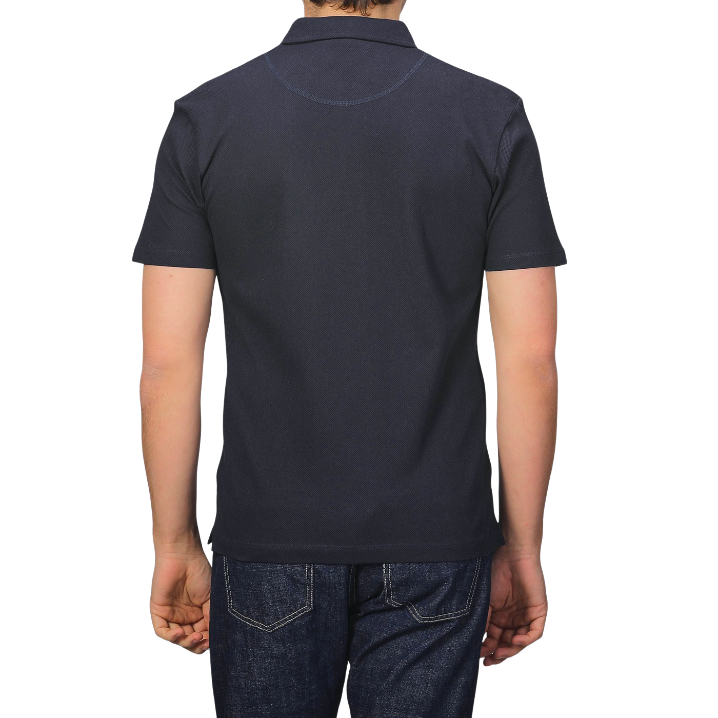 Rear view of a person in a Sunspel Midnight Blue Cotton Riviera Polo Shirt and jeans, standing against a plain background.