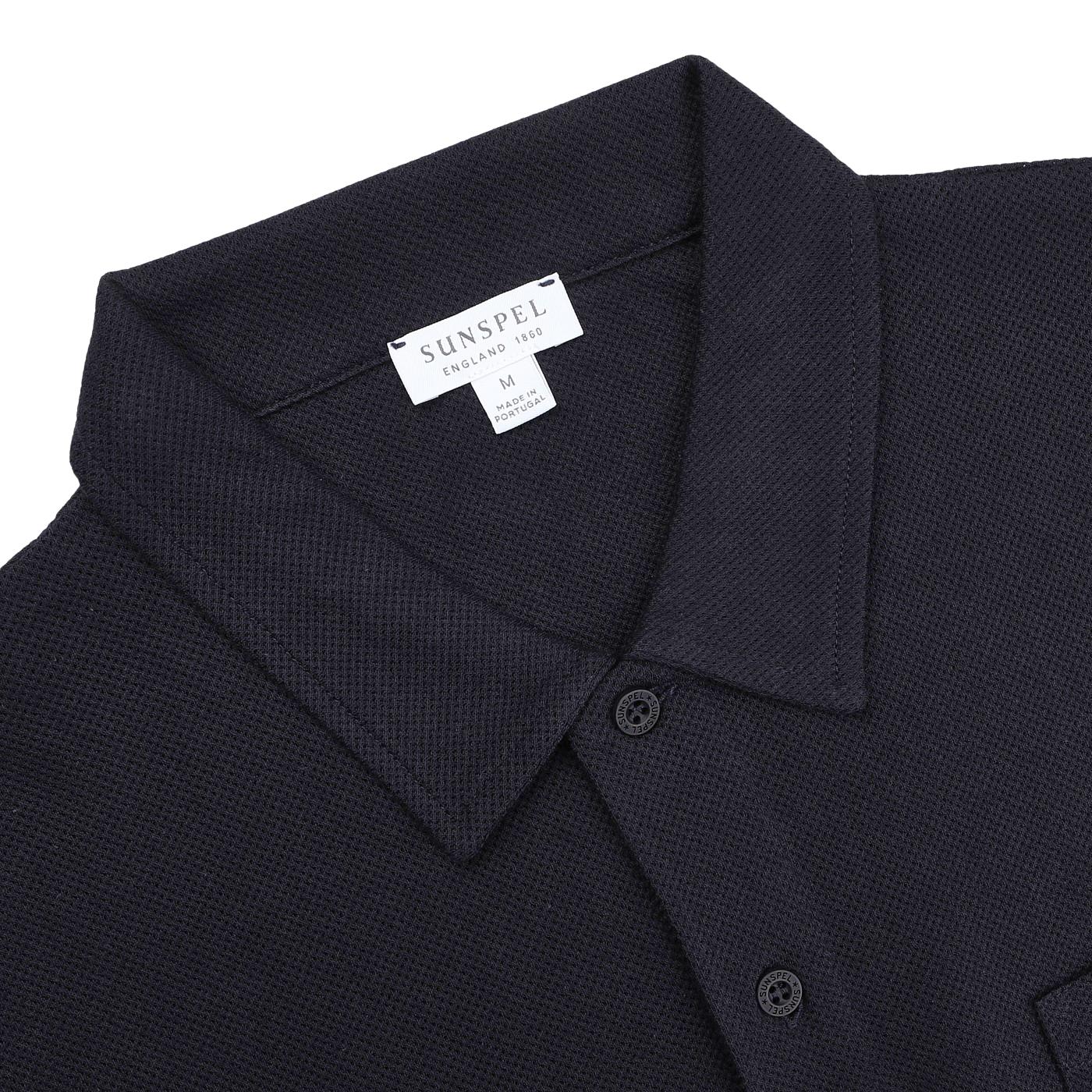 Check out the Midnight Blue Cotton Riviera Polo Shirt by Sunspel, a versatile staple featuring breathable cotton mesh, a collar, button placket, and visible "Made in England" and "Medium" branding.