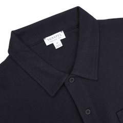 Check out the Midnight Blue Cotton Riviera Polo Shirt by Sunspel, a versatile staple featuring breathable cotton mesh, a collar, button placket, and visible "Made in England" and "Medium" branding.