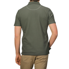 From the back, a person in a Sunspel Pine Green Cotton Riviera Polo Shirt and khaki pants exemplifies a contemporary aesthetic.