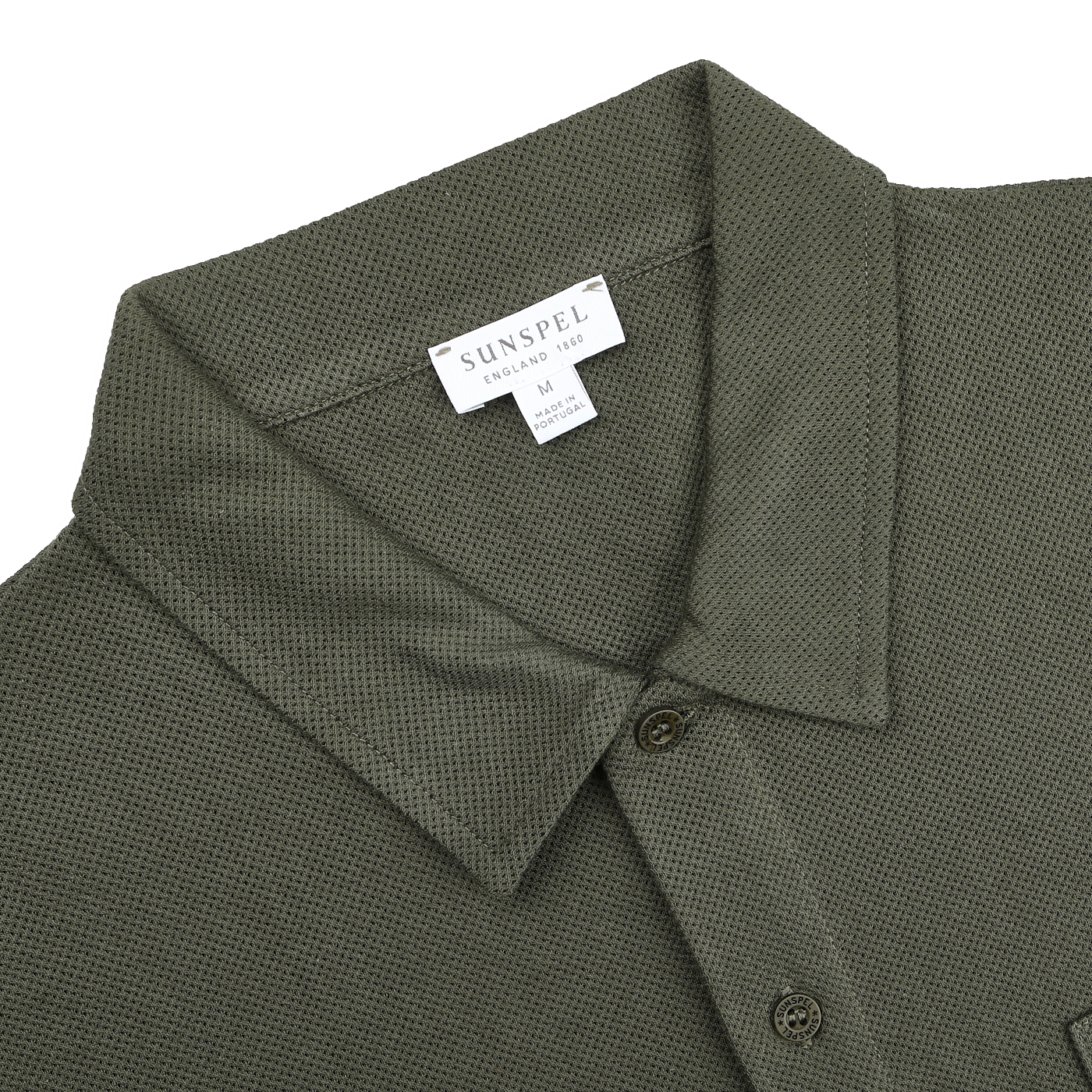 The Pine Green Cotton Riviera Polo Shirt by Sunspel is crafted from breathable cotton, featuring a collar and tag reading "Sunspel, England, 1860, Medium, Made in Portugal," blending classic style with a contemporary aesthetic.