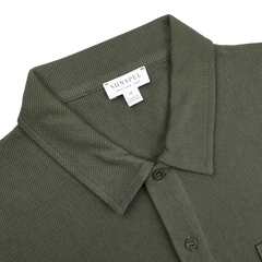 The Pine Green Cotton Riviera Polo Shirt by Sunspel is crafted from breathable cotton, featuring a collar and tag reading "Sunspel, England, 1860, Medium, Made in Portugal," blending classic style with a contemporary aesthetic.