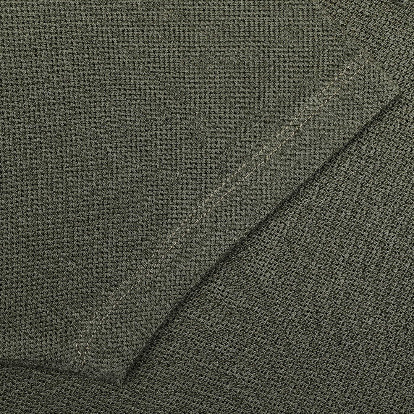 Close-up of the Pine Green Cotton Riviera Polo Shirt by Sunspel, highlighting its dark green textured fabric with visible stitching and contemporary aesthetic.