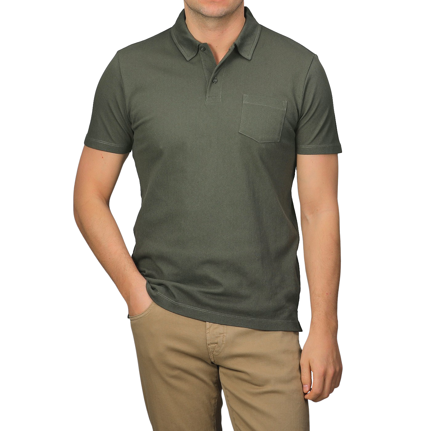 Dressed in a Sunspel Pine Green Cotton Riviera Polo Shirt with a chest pocket, paired with beige pants, one casually slips a hand in a pocket, epitomizing the contemporary and sophisticated style of its breathable cotton fabric.