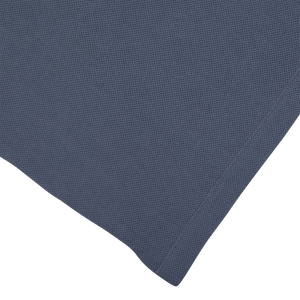 A Sunspel slate blue cotton napkin with a small square on it, reminiscent of James Bond.
