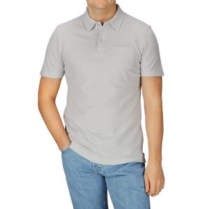 A man in a Smoke Grey Cotton Riviera Polo Shirt by Sunspel and jeans.