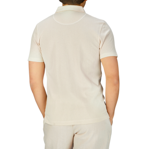 The man, wearing a white Undyed Cotton Riviera Polo Shirt, resembles James Bond in the stylish Sunspel design.