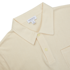 A beige Sunspel Undyed Cotton Riviera Polo Shirt with a pocket, perfect for channeling James Bond vibes.