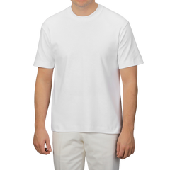 A person poses effortlessly against a neutral background, wearing a Sunspel White Supima Cotton Relaxed Fit T-shirt and matching pants, showcasing style and comfort.