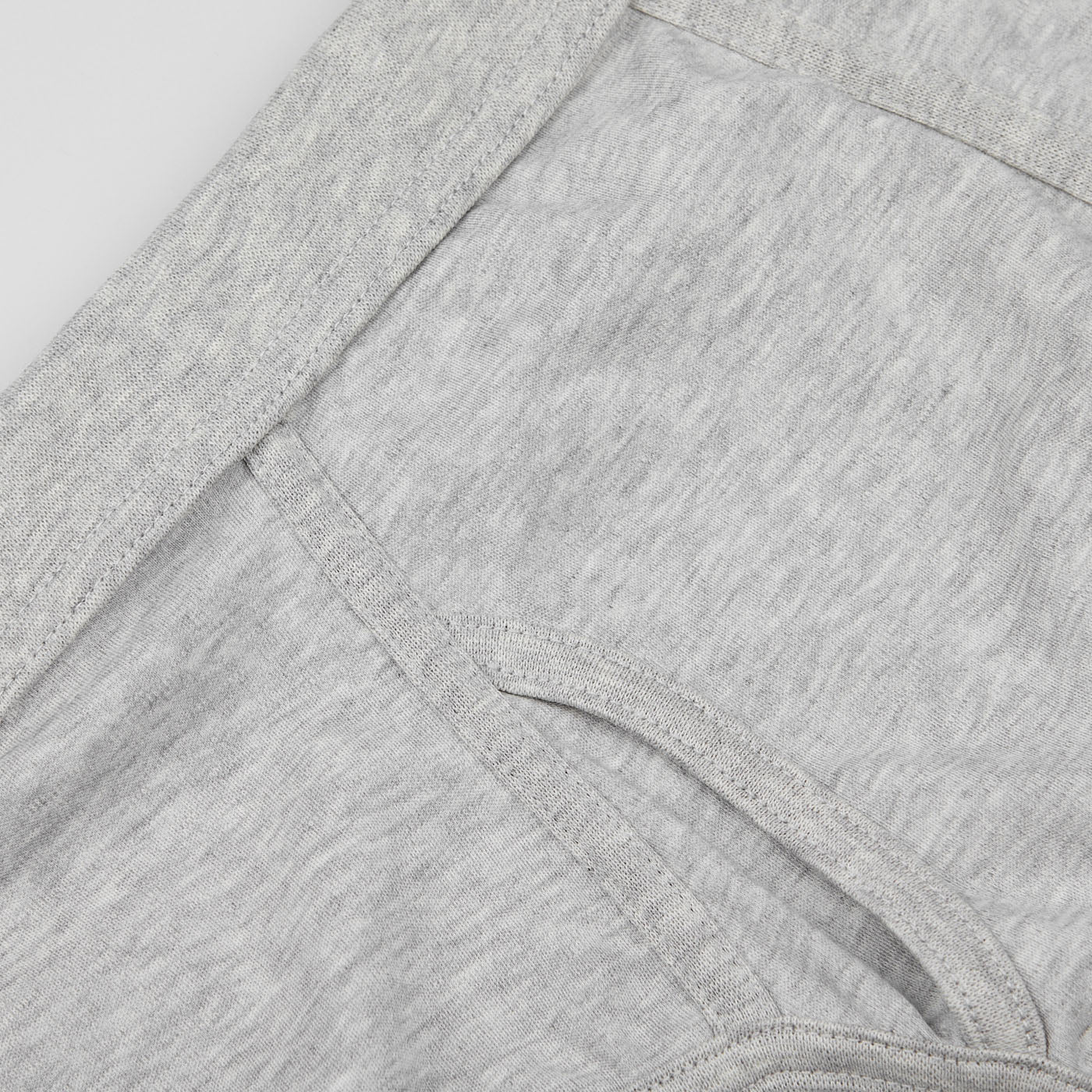 Close-up view of a light gray fabric detail with a curved seam and an attached pocket. The fabric, made from organic pima cotton, has a soft, heathered texture. This is part of the Grey Melange Pima Cotton Platan Briefs by The White Briefs.