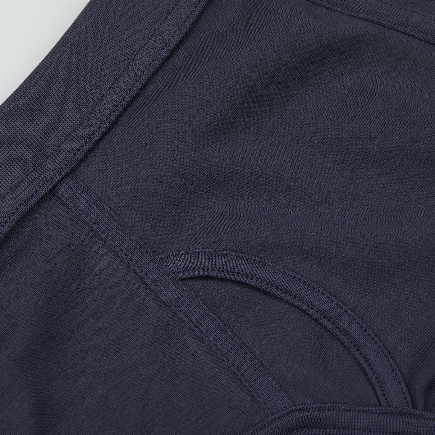 Close-up of a dark blue garment featuring seams and straps, reminiscent of a classic brief. The Parisian Night Pima Cotton Platan Briefs by The White Briefs exude the allure of a Parisian night thanks to their rich hue and are crafted from luxurious organic pima cotton.