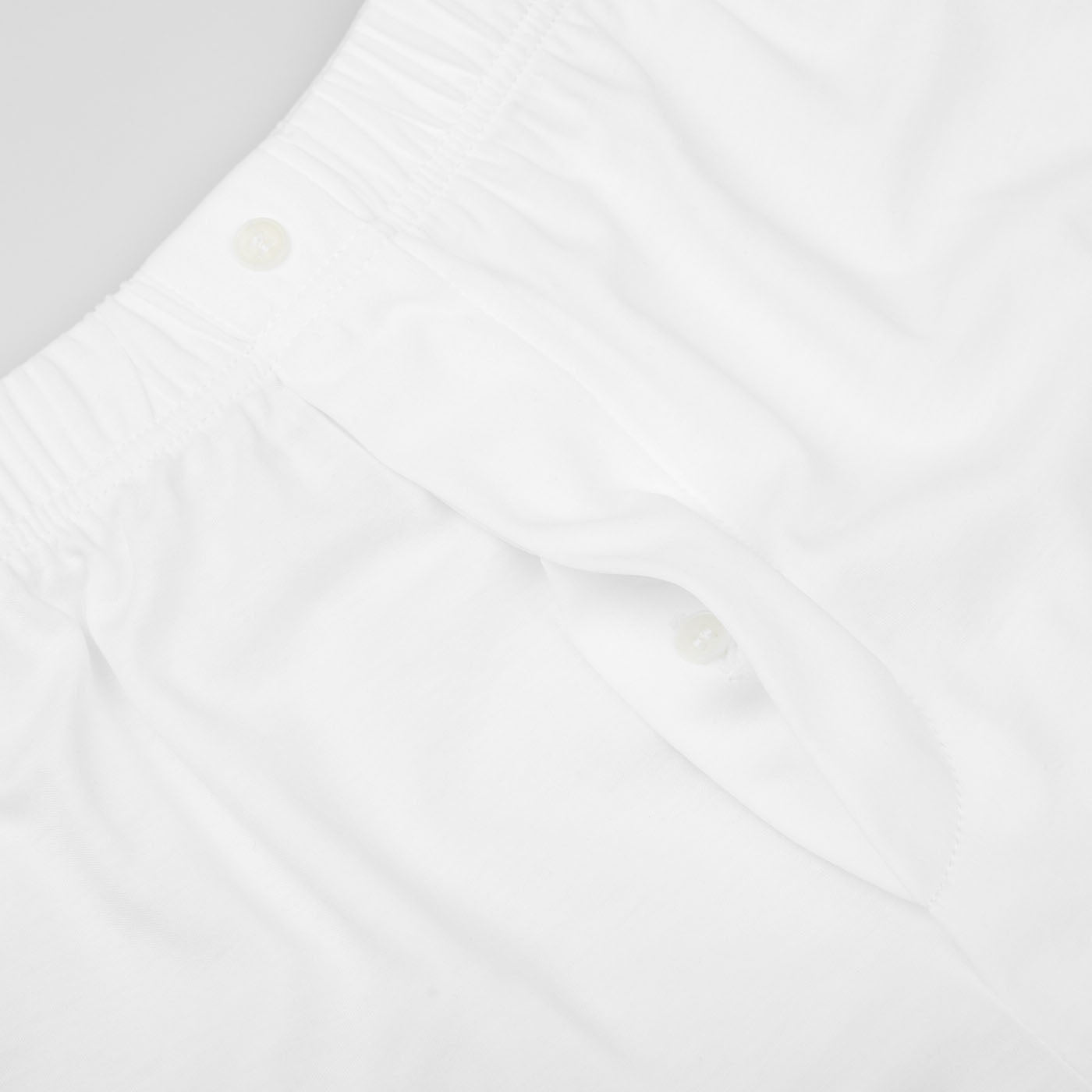 Close-up of a pair of classic White Lyocell Cotton Henner Boxers by The White Briefs featuring an elastic waistband and buttoned fly, made from a comfortable lyocell-cotton blend.