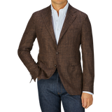Man in a Tagliatore Dark Brown Melange Wool Linen Silk Blazer and blue jeans with a white shirt, hands in pockets, cropped at the neck.