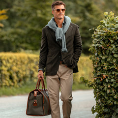 A man, wearing a Dark Green Wool Cashmere Vesuvio Blazer from Tagliatore, walking down the street carrying a bag.