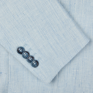 Close-up of a Tagliatore Vesuvio blazer in light blue linen-wool blend fabric with a herringbone pattern and a row of four dark buttons.