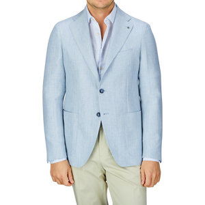 A man wearing a Tagliatore Light Blue Herringbone Linen Wool Vesuvio Blazer and cream trousers.