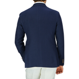 A person from behind wearing a Tagliatore navy blue herringbone cotton linen Vesuvio blazer with peak lapel and white trousers.