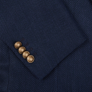 Close-up of a Navy Blue Herringbone Cotton Linen Vesuvio Blazer by Tagliatore with four gold buttons on a sleeve.