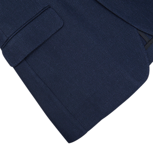Close-up of navy blue herringbone cotton-linen blend fabric with pocket detail, possibly from a garment such as a Tagliatore Vesuvio blazer.