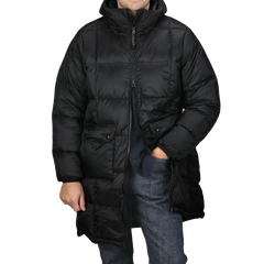 A person is wearing the Taion Black Nylon Down Padded Parka, with its hooded design and durable nylon exterior. Their hands are tucked into the jacket’s pockets, and the parka is zipped up to provide both comfort and style.