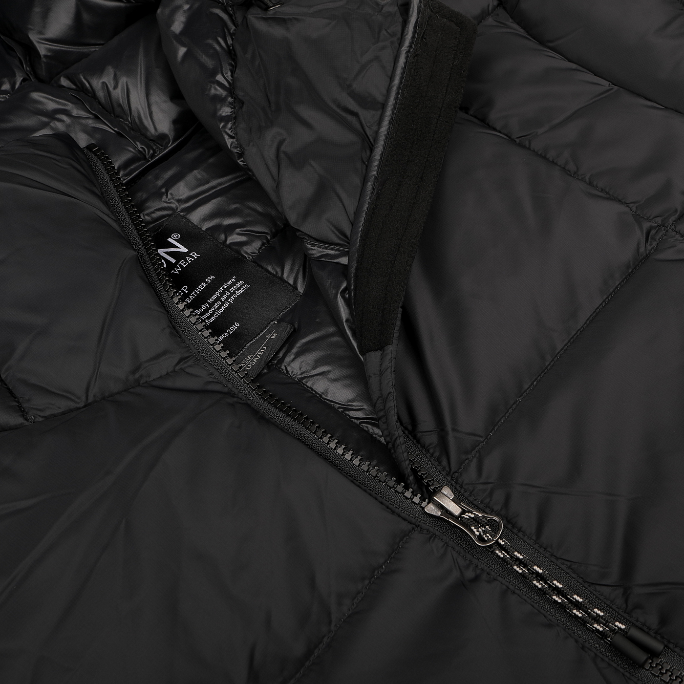 A close-up of an unzipped Taion Black Nylon Down Padded Parka highlights the zipper and inner fabric label. The durable nylon exterior combines with a sophisticated design that showcases the craftsmanship of this technical parka.