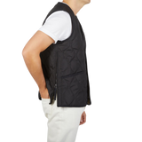 The back view of a man wearing a Taion Black Nylon Down V-Neck Button Vest filled with goose down.