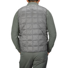 A person is seen from the back, dressed in a Charcoal Grey Nylon Down Padded Vest by Taion paired with matching gray pants.