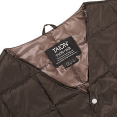 Close-up of a dark chocolate nylon down padded vest by Taion, featuring high-density nylon and goose down padding for warmth, with a visible label displaying the brand and size information.