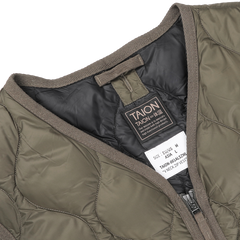 Close-up of a Dark Olive Nylon Down Padded Zip Vest, highlighting its high-density nylon construction with a gray interior, featuring labels displaying the "Taion" brand and size details.