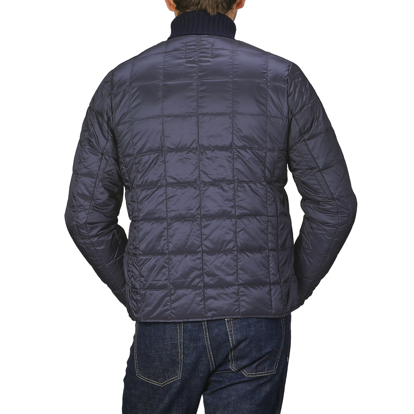 A person is depicted from behind clad in a Navy Blue Nylon Down Padded Jacket by Taion, paired with dark jeans, and set against a gray background.