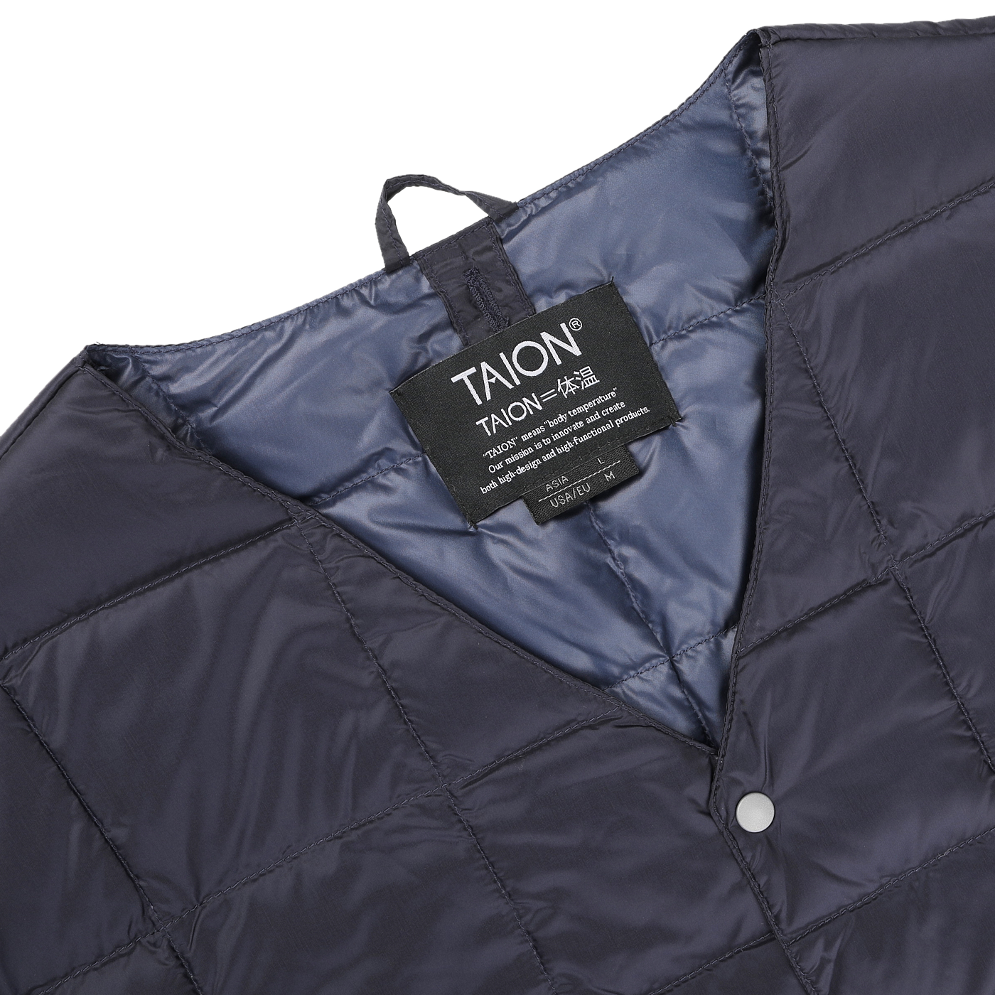 Close-up of a navy blue quilted jacket with a visible clothing tag labeled "Taion." This nylon down padded jacket, crafted from wind-resistant fabric, features a snap button closure and a hanging loop.