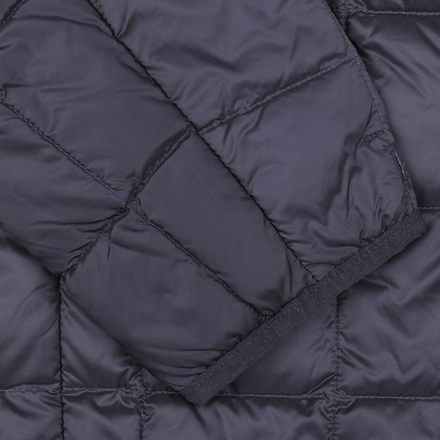 Close-up of a navy blue quilted fabric with a grid pattern, reminiscent of the Navy Blue Nylon Down Padded Jacket by Taion, featuring diagonal stitching and a folded section.