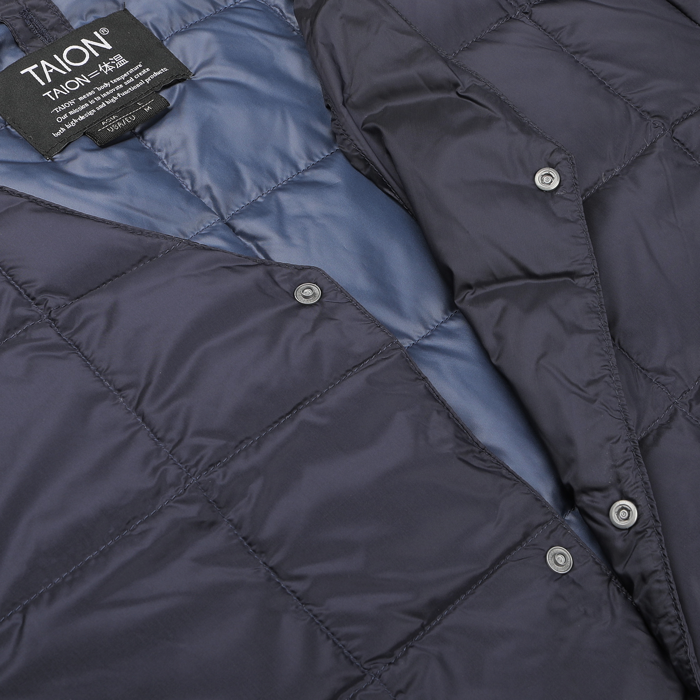 Close-up of the Navy Blue Nylon Down Padded Jacket with a quilted design, made from high-density nylon, featuring a clothing label reading "Taion." The interior showcases a smooth and glossy navy blue fabric.