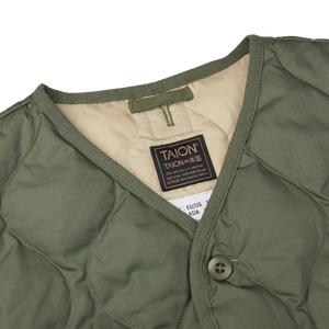 The back of a Taion Olive Green Nylon Down V-Neck Button Vest with a label on it, designed by a Japanese outerwear specialist.