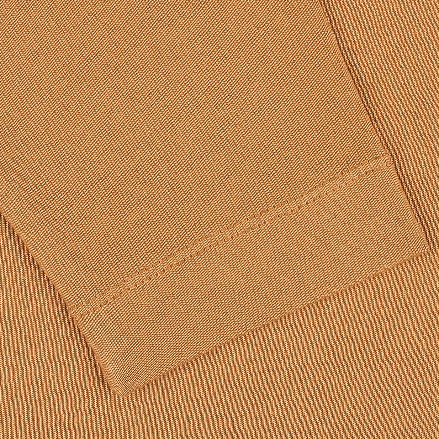 Close-up image of a folded, brick orange Tela Genova heavy organic cotton LS T-shirt with visible stitching details.