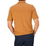 A man wearing a Brick Orange Heavy Organic Cotton T-Shirt from Tela Genova and dark pants, viewed from behind.