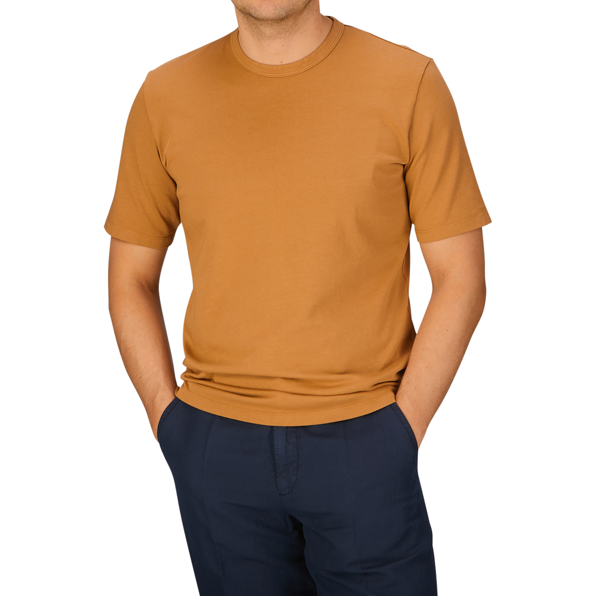 A person wearing a Brick Orange Heavy Organic Cotton T-Shirt from Tela Genova and dark pants, with their head cropped out of the frame.