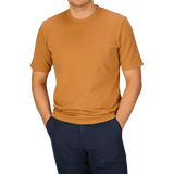 A person wearing a Brick Orange Heavy Organic Cotton T-Shirt from Tela Genova and dark pants, with their head cropped out of the frame.