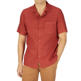 A man wearing a Brick Red Renato Linen Camp Collar Shirt by Tela Genova, giving off a summer feel.