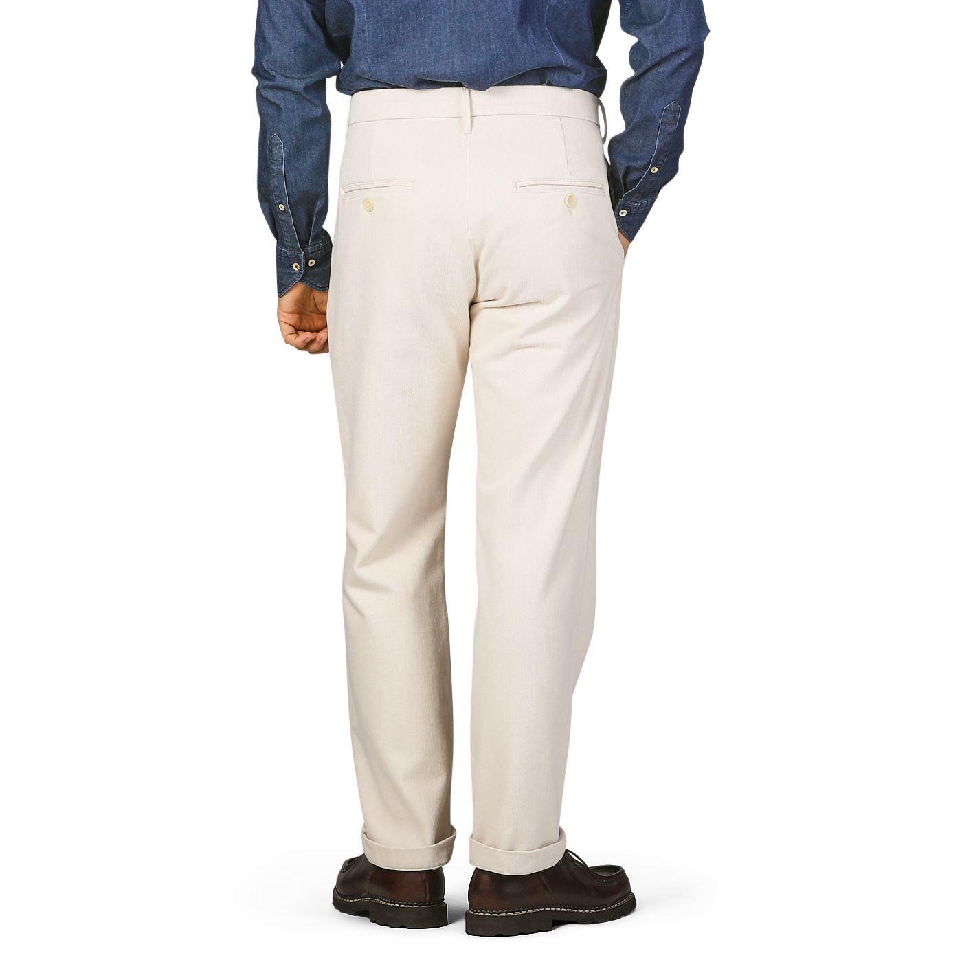 A person wearing Tela Genova Ecru Beige Cotton Wool Berardo Trousers and a blue denim shirt is standing with their back to the camera.