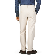 A person wearing Tela Genova Ecru Beige Cotton Wool Berardo Trousers and a blue denim shirt is standing with their back to the camera.