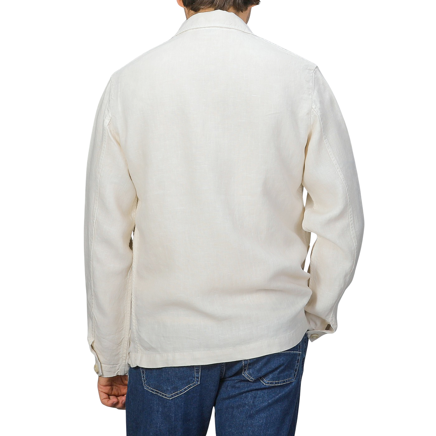 A person in a Tela Genova Ecru Pure Linen Camillo Jacket and blue jeans casually faces away from the camera against a gray backdrop.