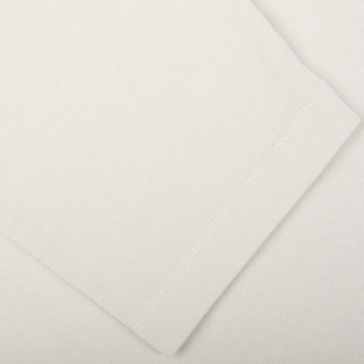 Close-up image of the hem of the Ecru White Heavy Organic Cotton LS T-Shirt from Tela Genova, showing detailed stitching on premium organic cotton fabric.