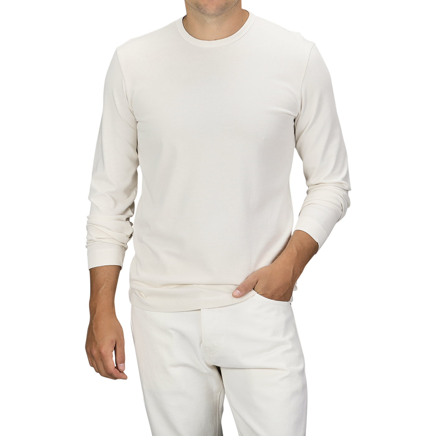 A person wearing an Ecru White Heavy Organic Cotton LS T-Shirt and white pants made of organic cotton from Tela Genova, standing against a plain background, with one hand in their pocket.